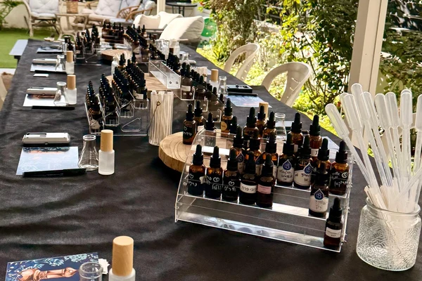 שולחן ערוך לסדנת בישום קבוצתית עם חומרי גלם, פיפטות וניירות הרחה