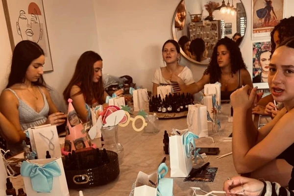 קבוצת נערות בסדנת בישום לבת מצווה סביב שולחן ערוך